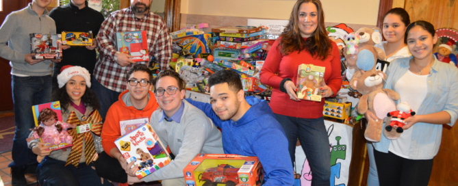 Head of School Ms. Iphigenia Romanos, Director of Academy Operations Mr. Albert C. Corhan and proud Adelphi parent and Maimonides employee Ms. Iris Iglesias are pictured with Student Advisory Board members displaying some of the toys collected.
