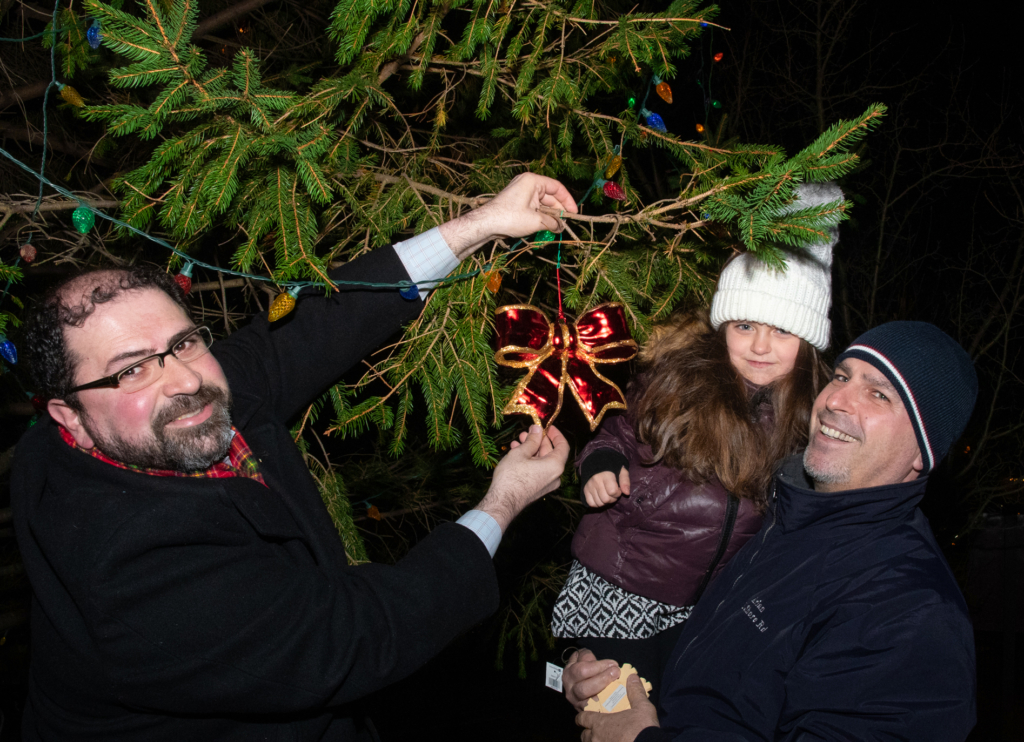 Director of Academy Operations Mr. Albert C. Corhan helps Lower Schooler Vanessa and dad hang an ornament on Adelphi’s community tree!