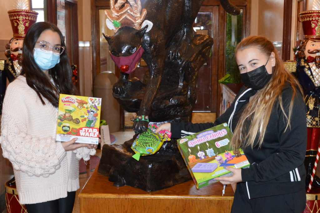 Student Advisory Board members Maxelle and Ilona pose before placing toys in the donation bin.